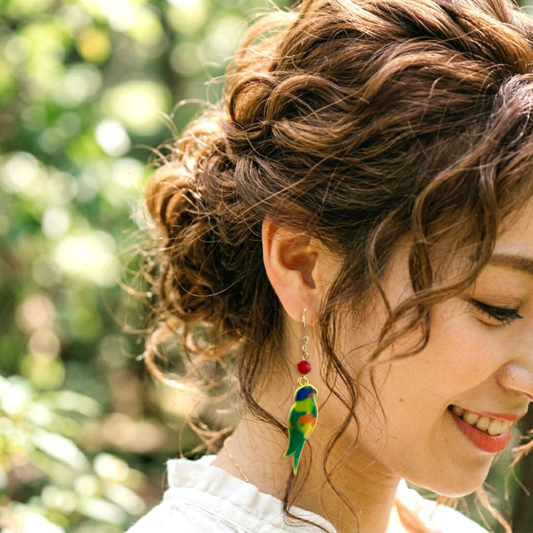 On-model style photo showcasing the fit, drop length, and scale of the colorful upcycled plastic bird silhouette earrings. Rainbow Lorikeet variant.