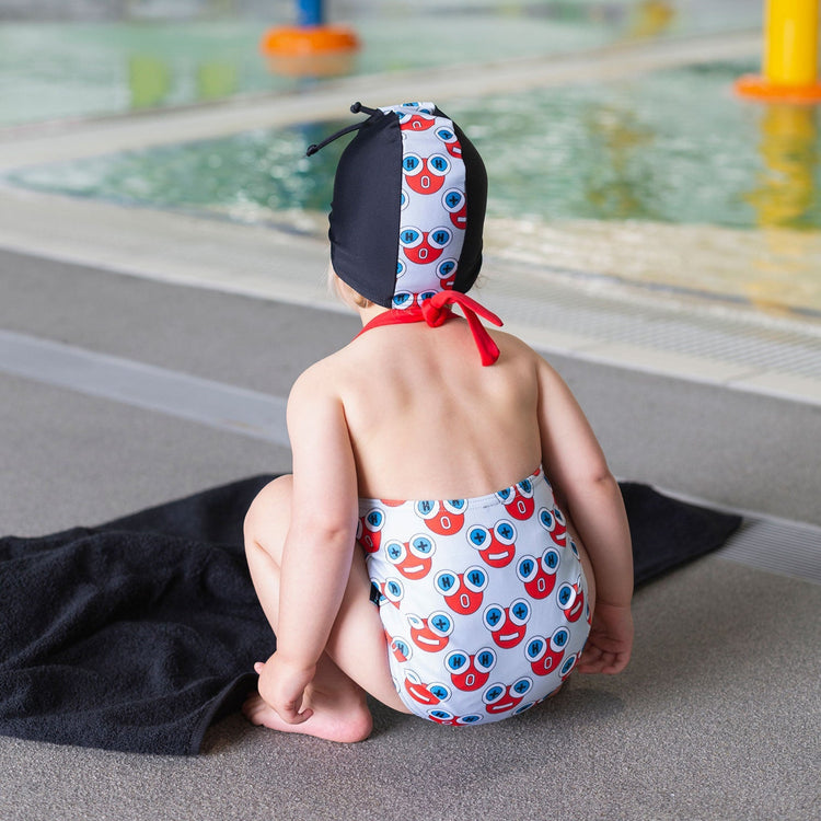 Baby wearing the Tyoub H2O water print halterneck one piece swimsuit back view at a pool.