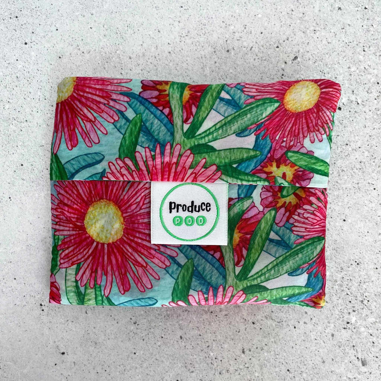 Close up view of the lightweight sixty gram reusable grocery bag folded entirely inside its own integrated self storing travel pouch for compact pocket storage. Sea Fig variant.