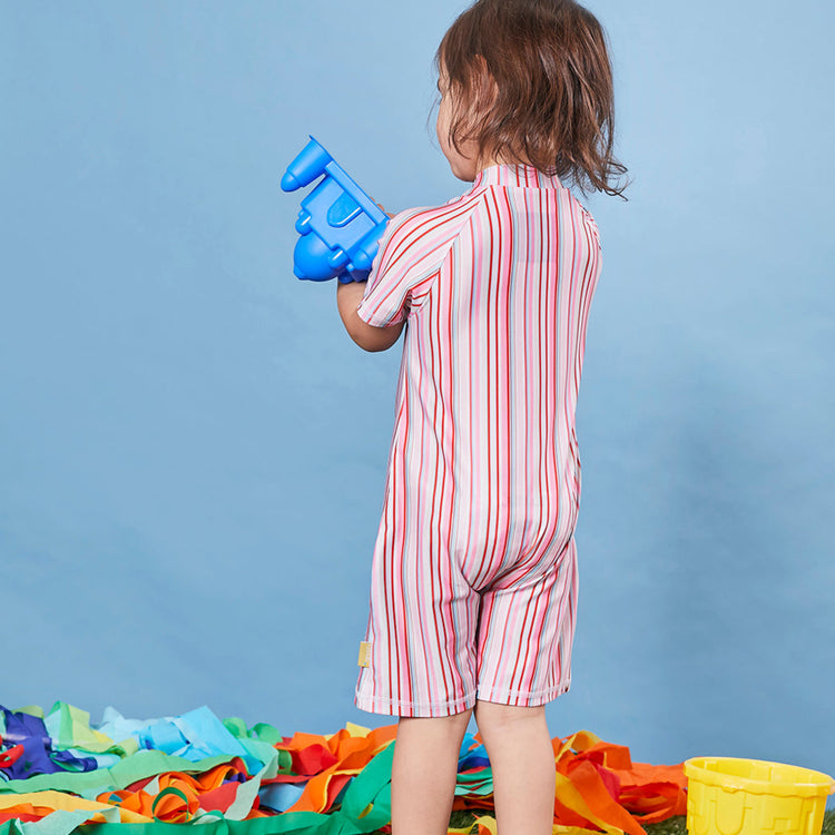 Toddler wearing a Tyoub short sleeve one piece swimsuit in pink gelato stripe pattern in a studio.