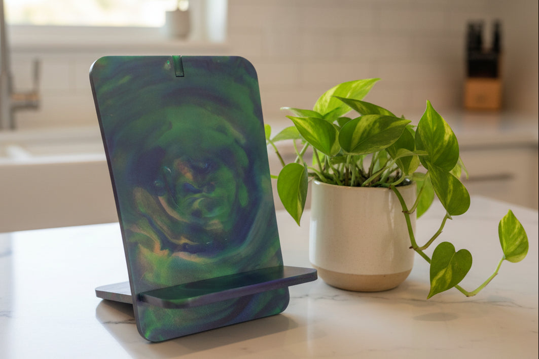 Mother Earth recycled plastic mobile phone stand on a kitchen banchtop next to a small pot plant