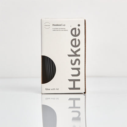 Large 12oz HuskeeOriginal reusable coffee cup featuring the signature vertical ribbed design made from sustainable coffee husk waste in charcoal in box.