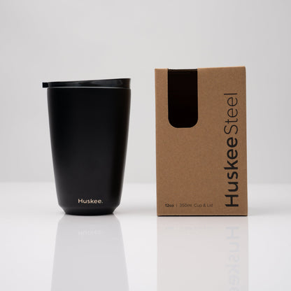 Large 12oz HuskeeSteel reusable coffee cup with matching stopper lid made from 91% recycled vacuum insulated stainless steel in black with box.