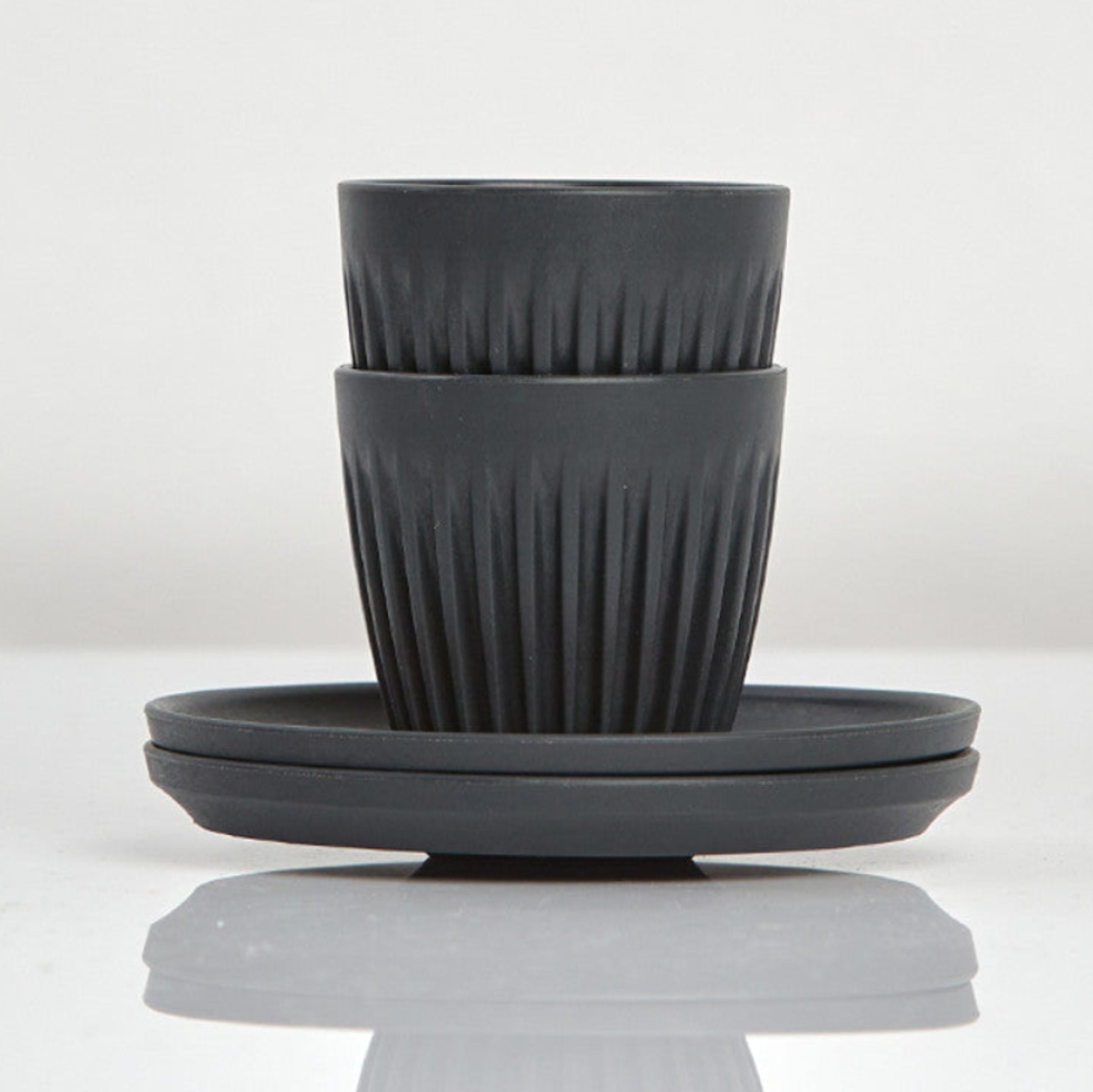 Set of 2 small 3oz HuskeeOriginal reusable espresso cups with saucers featuring the signature vertical ribbed design made from organic coffee husk waste in charcoal.