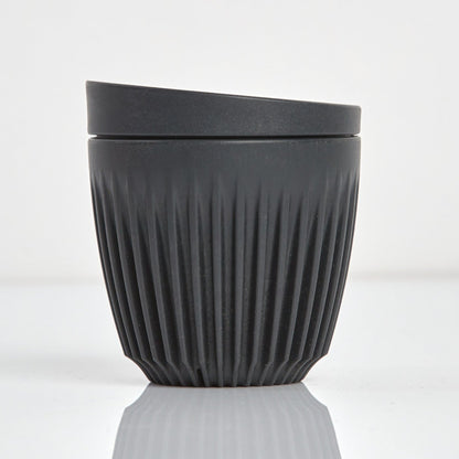 A 6oz HuskeeOriginal reusable coffee cup featuring signature ribbed design made from sustainable coffee husk waste charcoal.