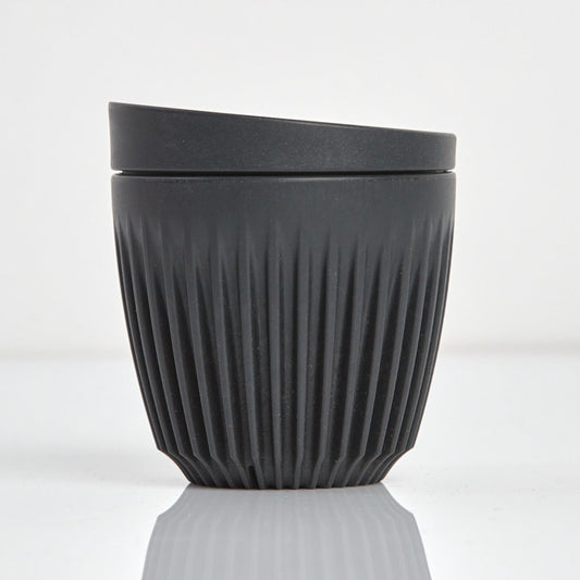 A 6oz HuskeeOriginal reusable coffee cup featuring the signature vertical ribbed design made from sustainable coffee husk waste charcoal.