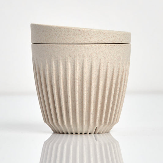 A 6oz HuskeeOriginal reusable coffee cup featuring the signature vertical ribbed design made from sustainable coffee husk waste in natural.