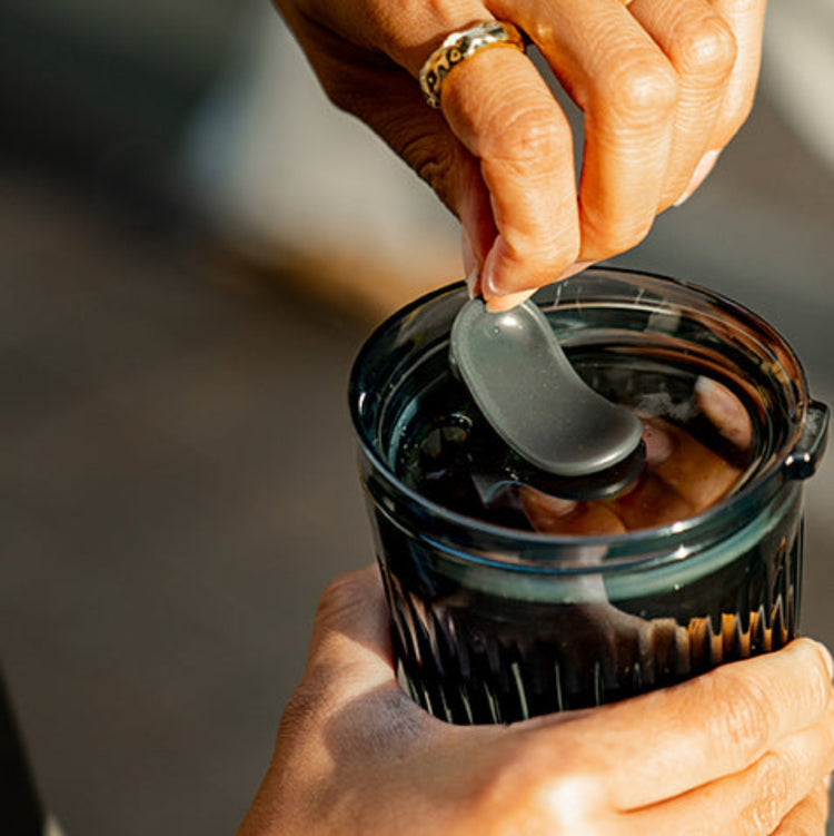 A small 6oz HuskeeRenew translucent reusable coffee cup made from high-performance recycled polymer with lid in use