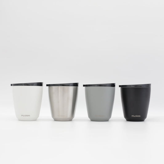 Four small 6oz HuskeeSteel reusable coffee cups with matching stopper lid made from 91% recycled vacuum insulated stainless steel showing the four colours available.