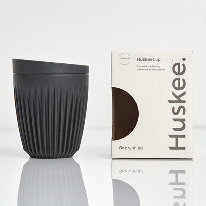 Standard 8oz HuskeeOriginal reusable coffee cup featuring the signature vertical ribbed design made from sustainable coffee husk waste in charcoal with box.