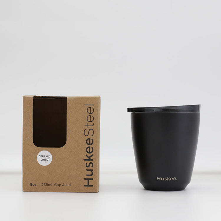 Standard 8oz HuskeeSteel reusable coffee cup with matching stopper lid made from 91% recycled vacuum insulated stainless steel in black with box.