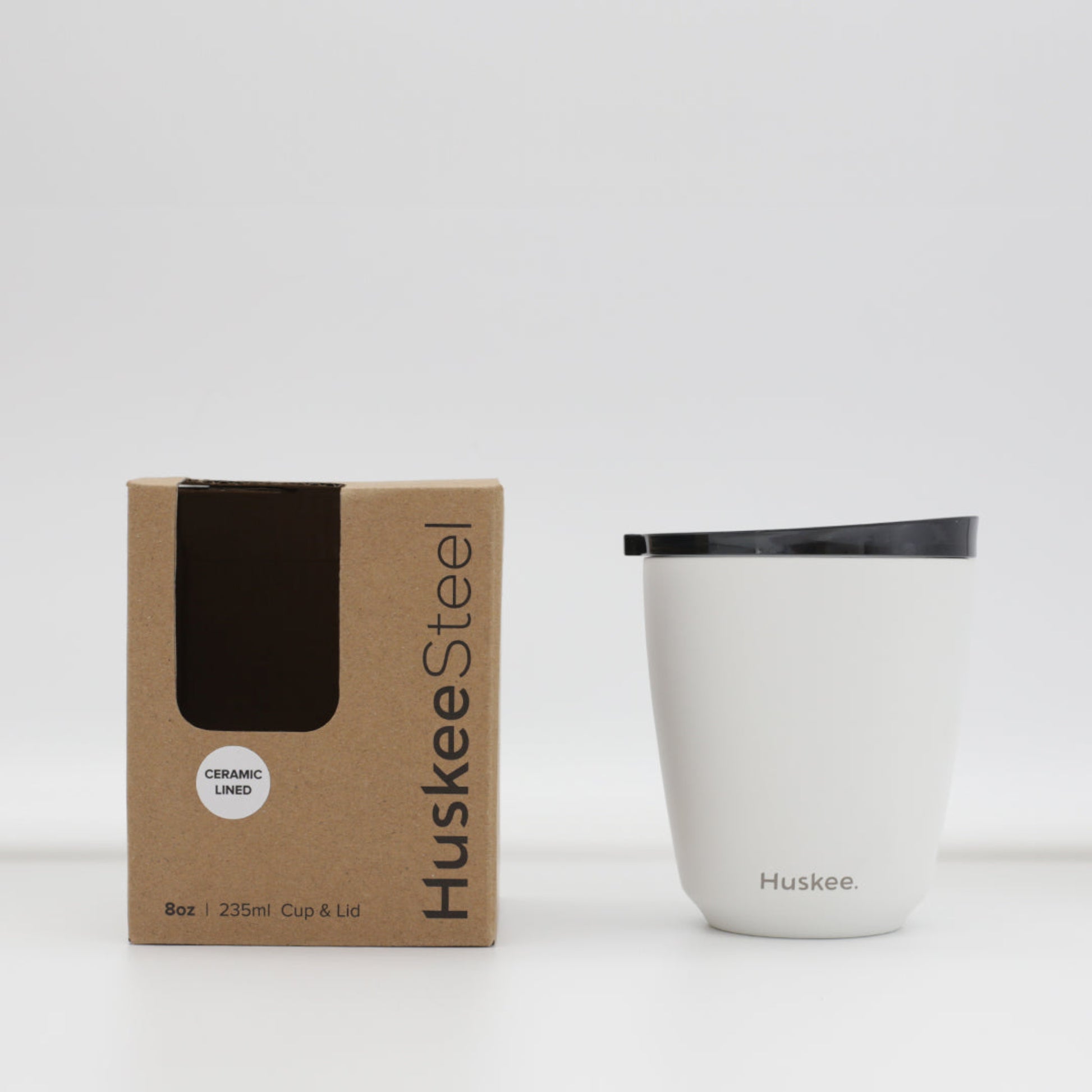 Standard 8oz HuskeeSteel reusable coffee cup with matching stopper lid made from 91% recycled vacuum insulated stainless steel in white with box.