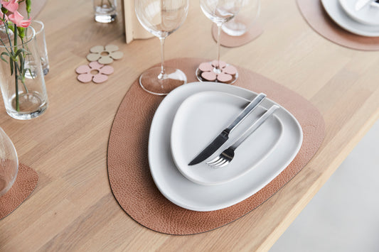 LIND DNA Curve Table Mat in Hippo finish on a wooden table set with white plates, glasses and cutery