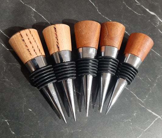 Set of six wooden and metal bottle stoppers on a dark surface