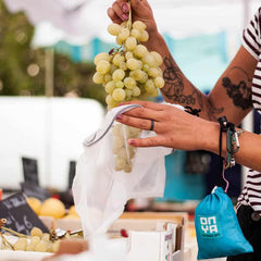 Person putting grapes into mesh produce bag in a fruit shop