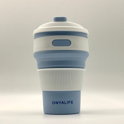 Collapsible 350ml silicone coffee cup with secure lid and heat-protective sleeve, shown expanded and collapsed with its reusable storage pouch. Shown in Powder Blue
