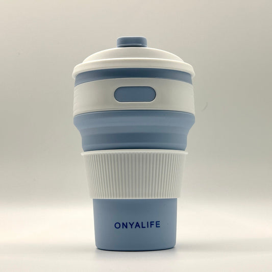 Collapsible 350ml silicone coffee cup with secure lid and heat-protective sleeve, shown expanded and collapsed with its reusable storage pouch. Shown in Powder Blue