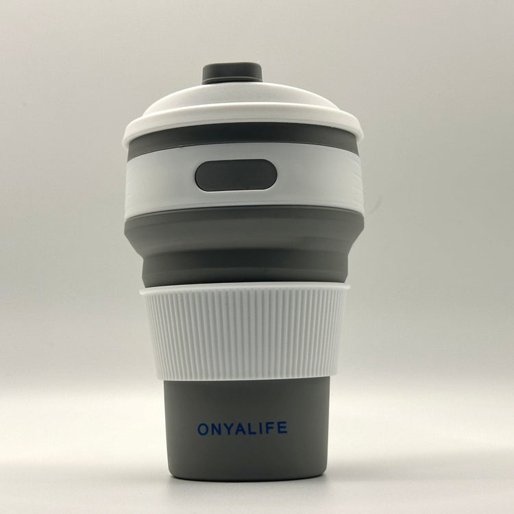 Collapsible 350ml silicone coffee cup with secure lid and heat-protective sleeve, shown expanded and collapsed with its reusable storage pouch. Shown in Slate Grey