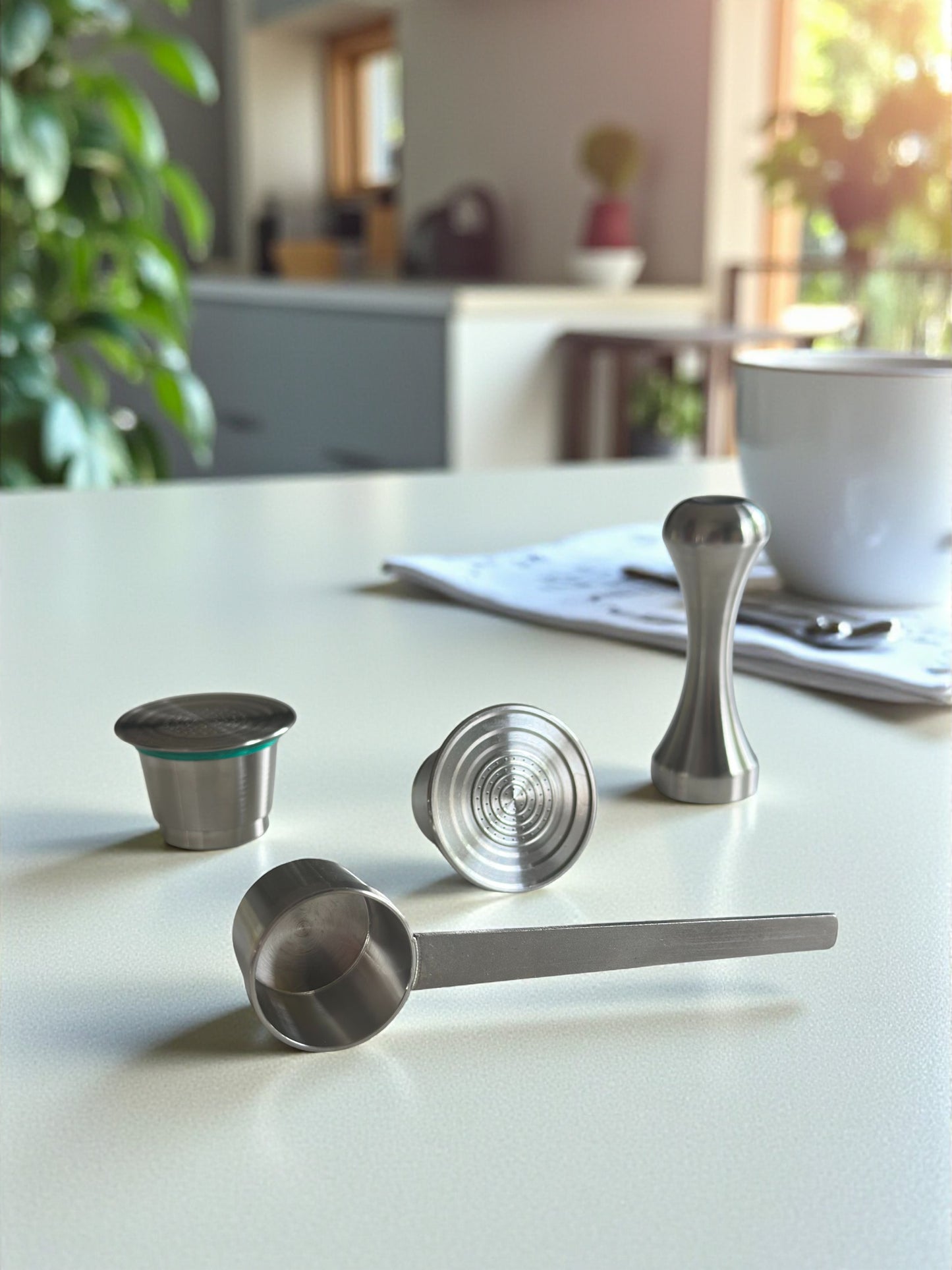 Two Pod Star Nesspresso Original reusable stainless steel coffee pods on a kitchen bench with a scoop and tamper