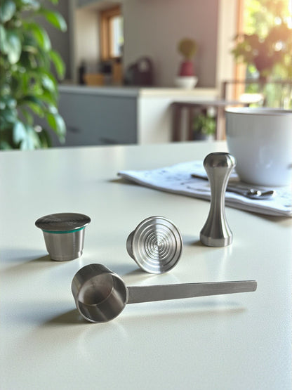 Two Pod Star Nesspresso Original reusable stainless steel coffee pods on a kitchen bench with a scoop and tamper