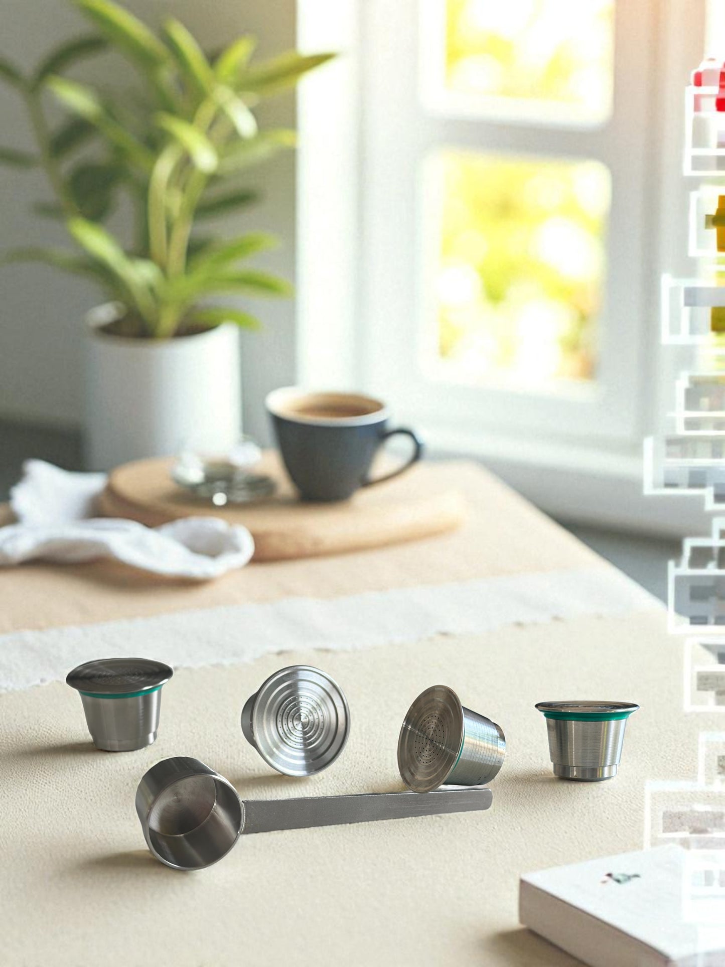 Four Pod Star Nesspresso Original reusable stainless steel coffee pods on a kitchen bench with a scoop and cup of coffee in the background