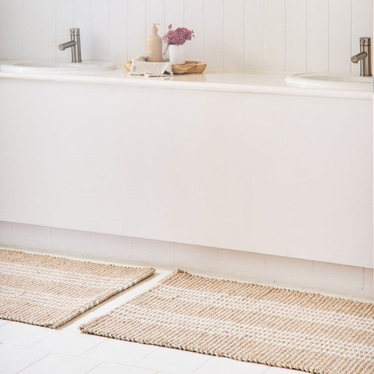 Mould and fade resistant absorbent bathroom runner mat in natural white stripe placed next to a bathroom vanity.