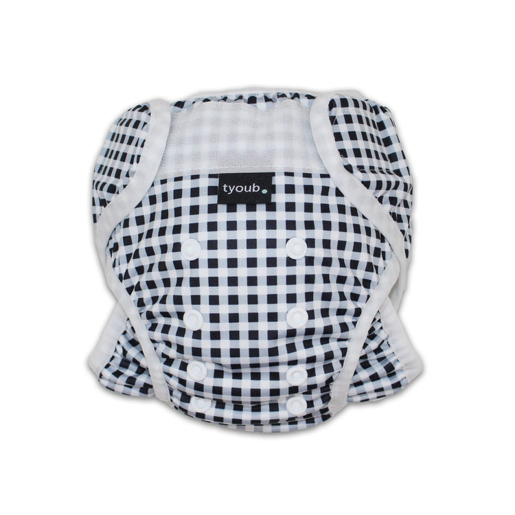 Close-up of an adjustable reusable baby swim nappy with snap buttons in a black gingham check pattern.