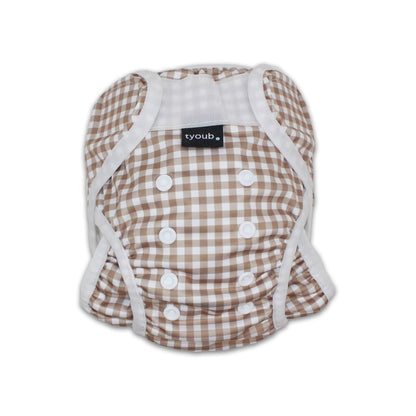 Close-up of an adjustable reusable baby swim nappy with snap buttons in a fawn gingham check pattern.