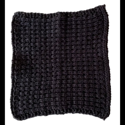 Black handmade knitted dishcloth made from absorbent recycled cotton for kitchen and bathroom use on a white background.