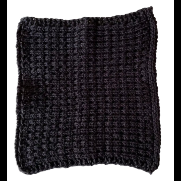 Black handmade knitted dishcloth made from absorbent recycled cotton for kitchen and bathroom use on a white background.