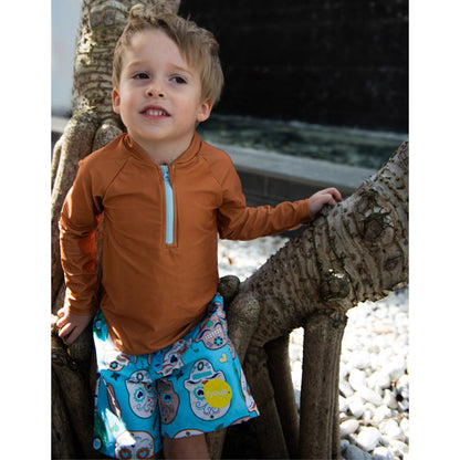 Young boy wearing aqua sugar skull pattern swim boardshorts outdoors in Australia.