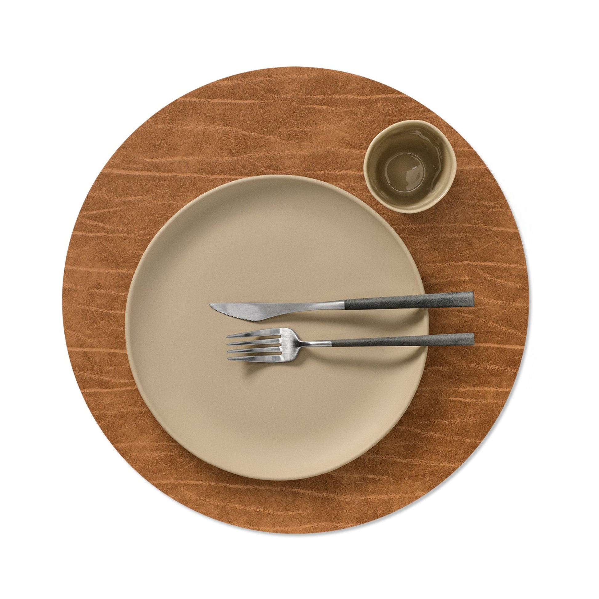 Circle recycled leather placemat featuring the signature LIND DNA Buffalo texture with plate setting and cup in nature.
