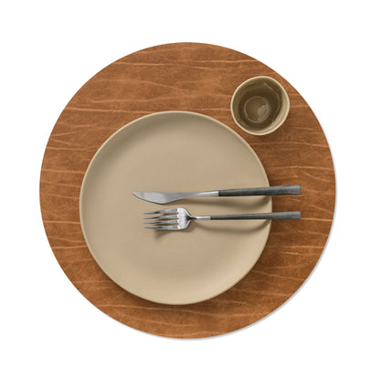 Circle recycled leather placemat featuring the signature LIND DNA Buffalo texture with plate setting and cup in nature.