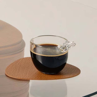 Curve recycled leather coaster featuring the signature LIND DNA bull texture on a glass table with a cup of coffee in a glass cup.