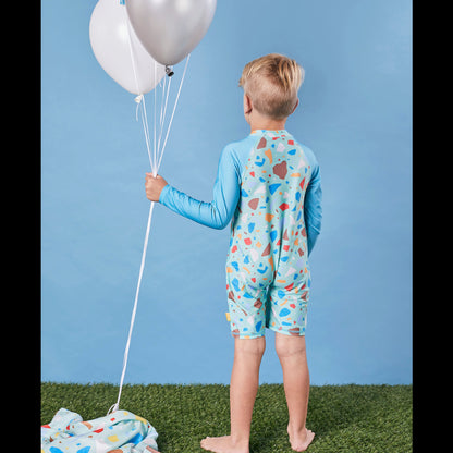 Child wearing the Tyoub long sleeve turquoise ocean glass sunsuit bather in a studio setting back view.