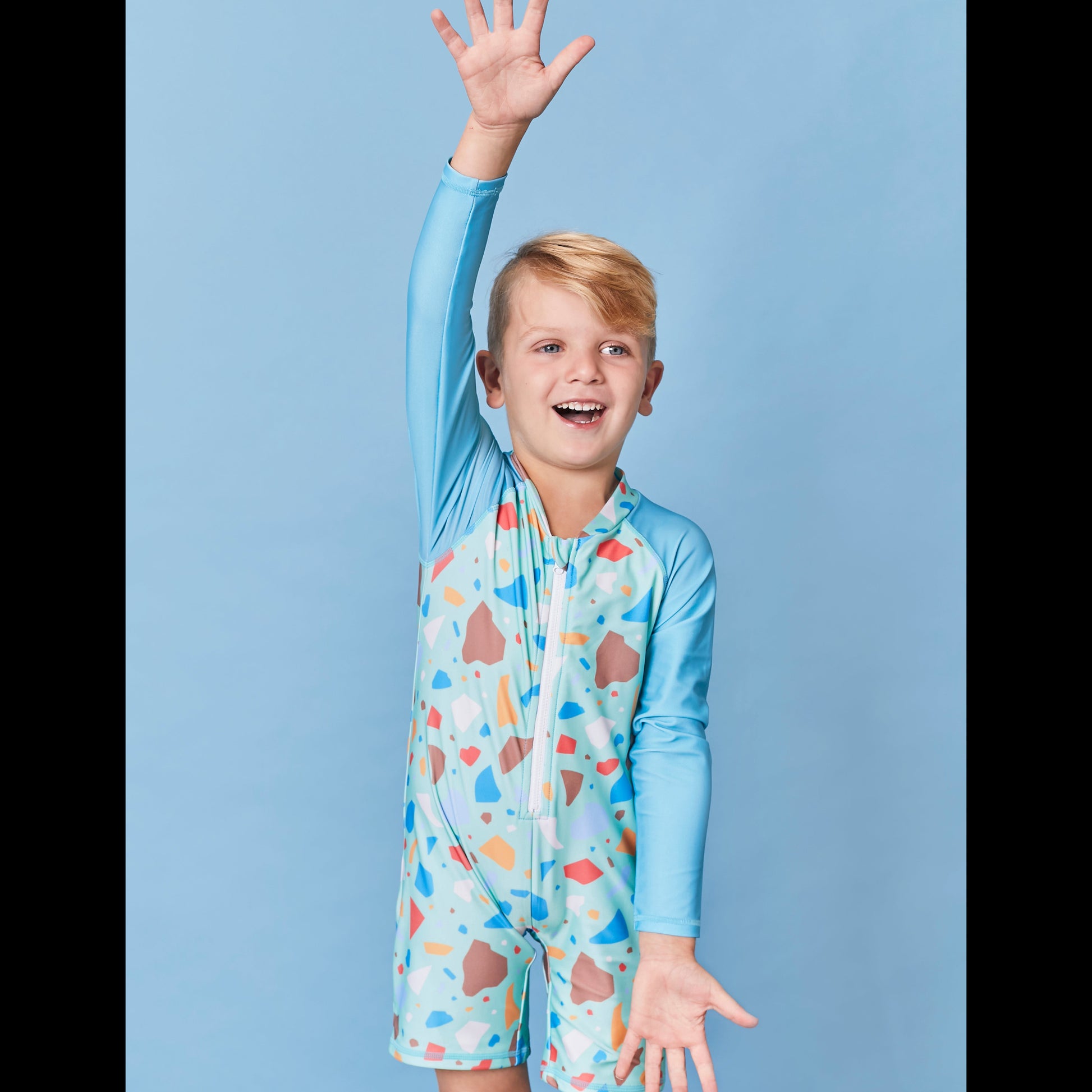 Child wearing the Tyoub long sleeve turquoise ocean glass sunsuit bather in a professional studio setting.