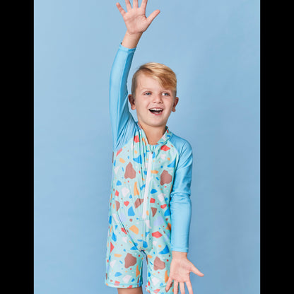 Child wearing the Tyoub long sleeve turquoise ocean glass sunsuit bather in a professional studio setting.