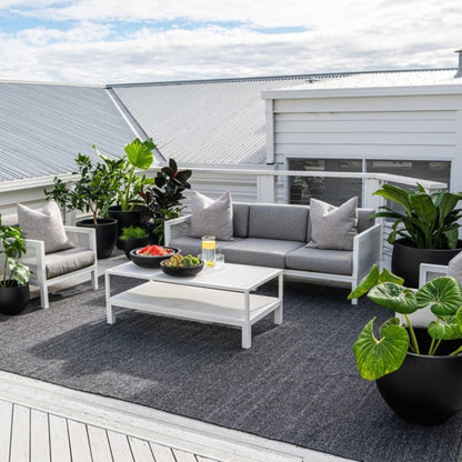 Zebra Home Clements charcoal grey large area rug styled under a modern outdoor lounge setting on a residential patio deck.