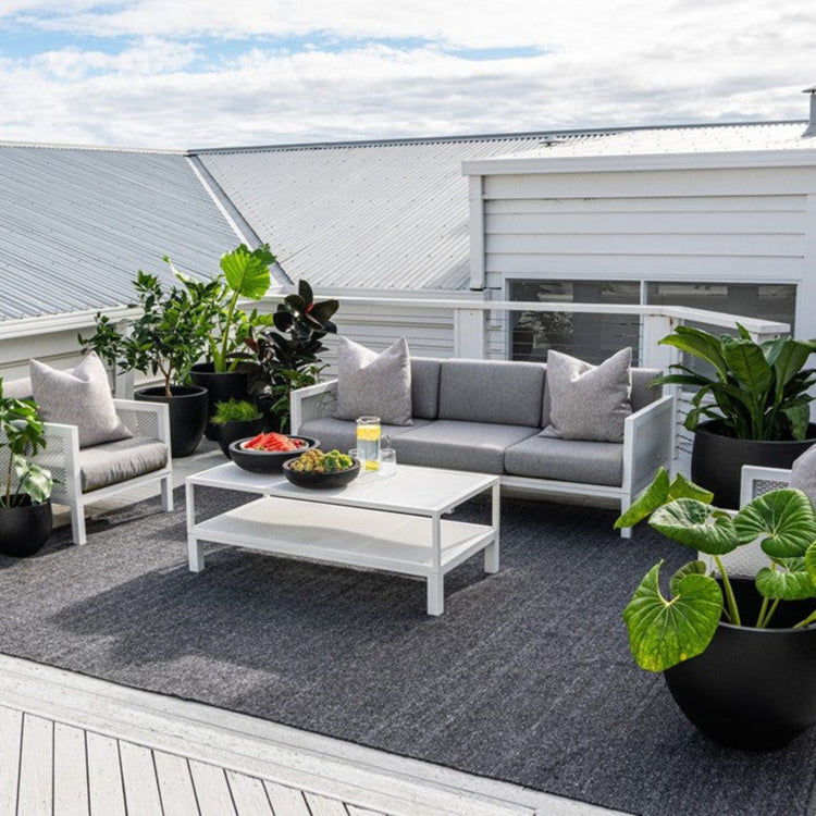 Zebra Home Clements charcoal grey large area rug styled under a modern outdoor lounge setting on a residential patio deck.