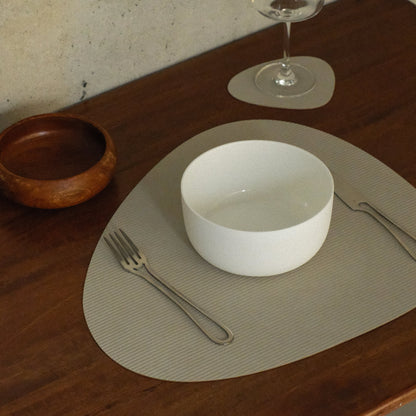 Curve recycled leather placemat featuring the signature LIND DNA Corduroy texture on a table set with knife, fork, bowl, glass and wooden bowl.