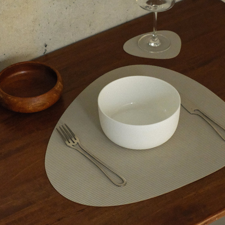 Curve recycled leather placemat featuring the signature LIND DNA Corduroy texture on a table set with knife, fork, bowl, glass and wooden bowl.