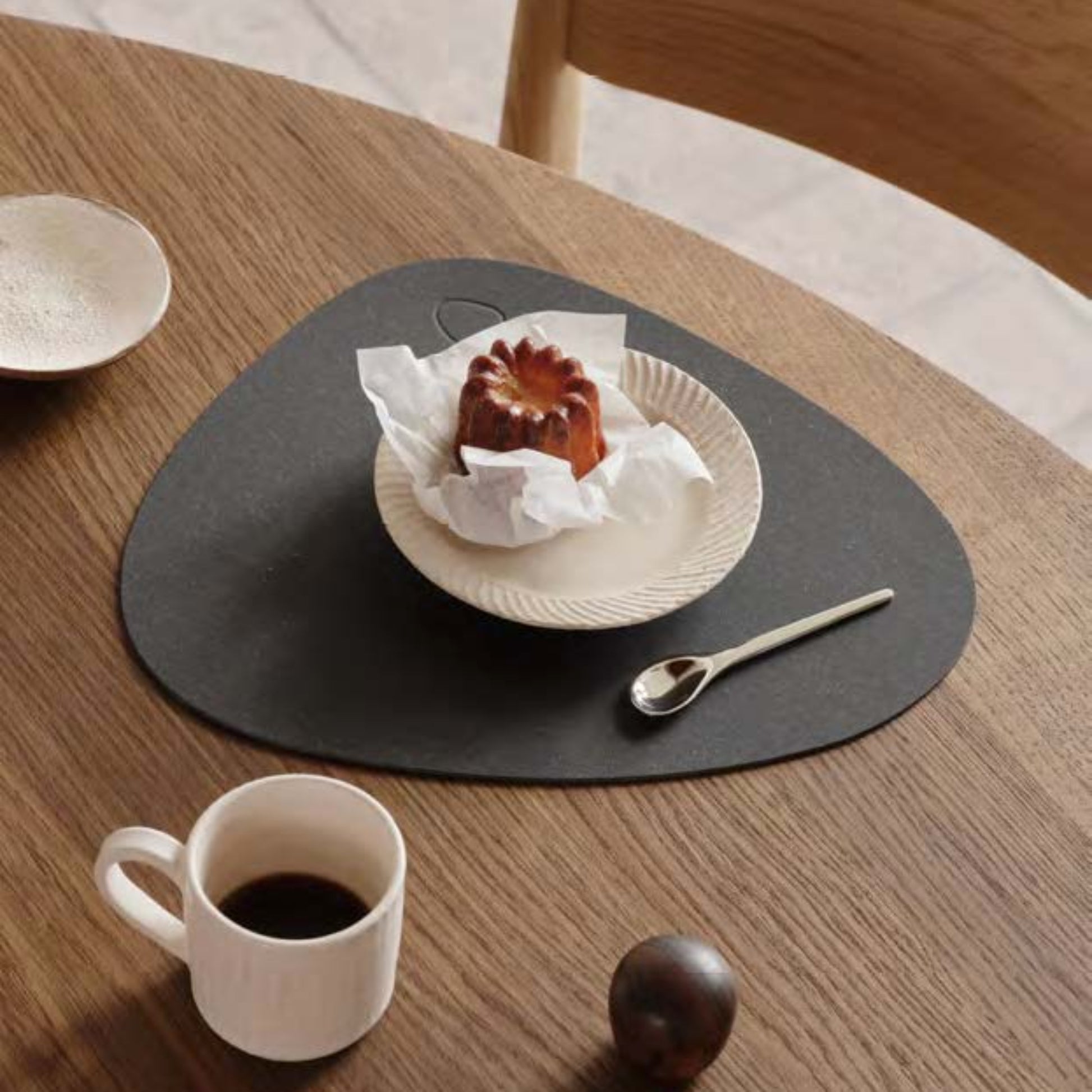Curve recycled leather placemat featuring the signature LIND DNA Core texture on a table set with plate, saucer, spoon and cup.