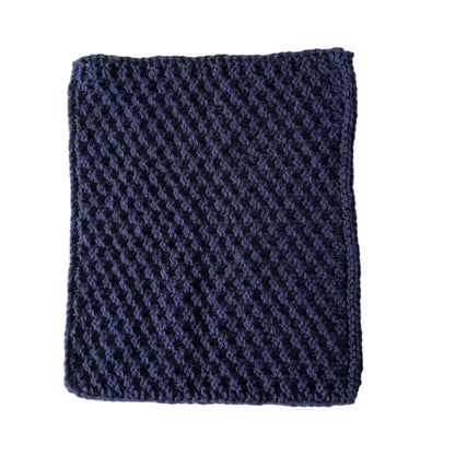 Dark blue handmade knitted dishcloth made from absorbent recycled cotton for kitchen and bathroom use on a white background.