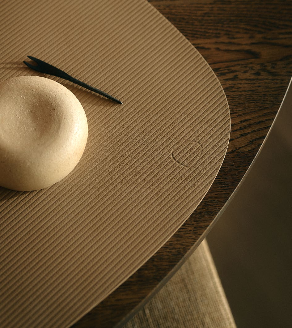 Recycled leather tablemats with a small object on a wooden surface