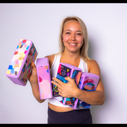 A selection of Wild Mingo Yoga blocks being held by a yoga practitioner in a studio.