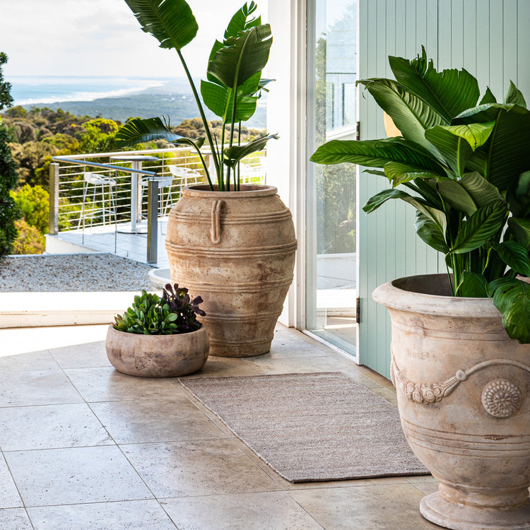 Durable Zebra Home Fraser beige flatweave runner rug styled next to large potted plants on a balcony patio.