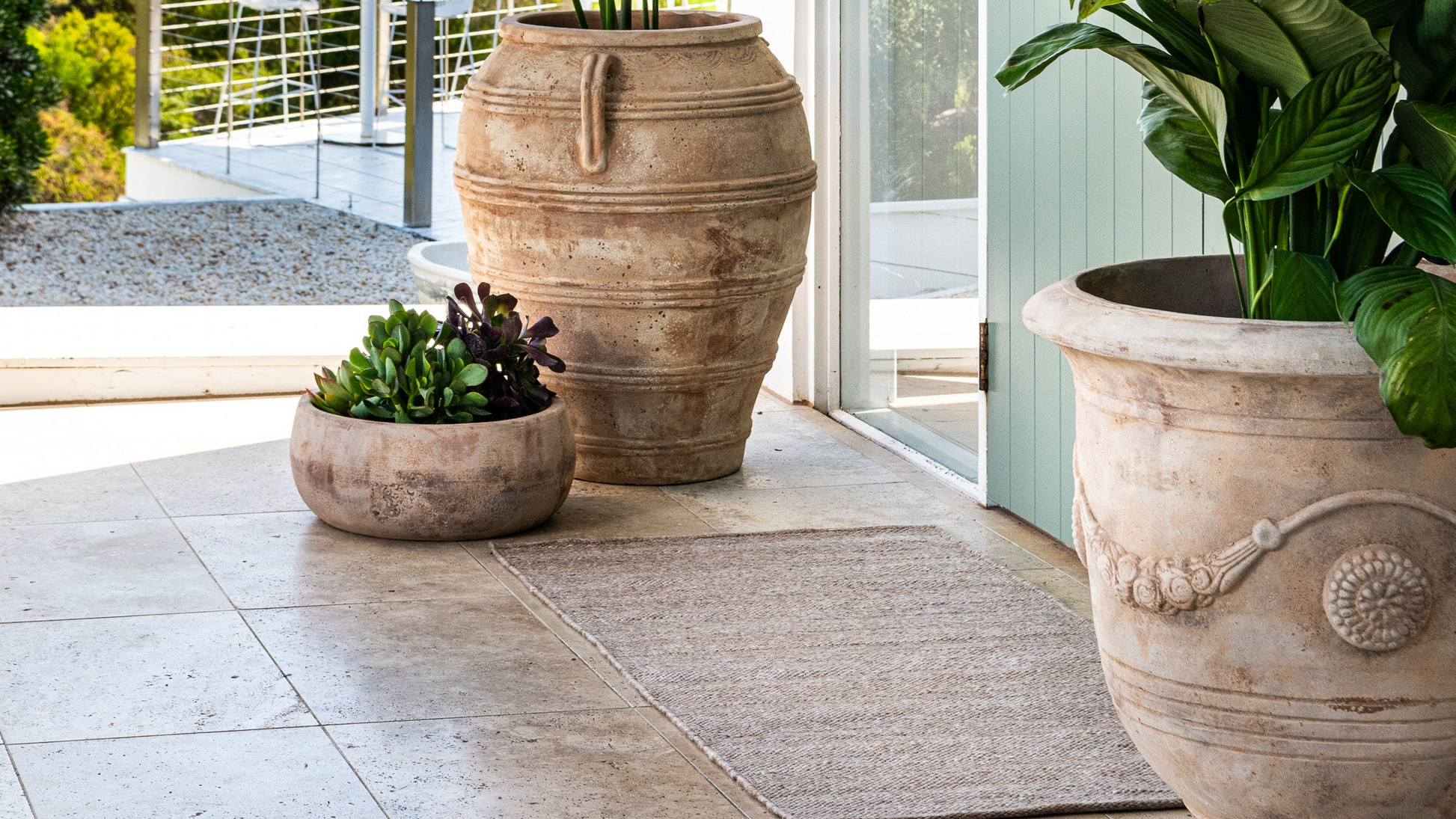 Warm minimalism outdoor area with potted plants in earthy tones and a Zebra Home recycled PET indoor/outdoor rug.