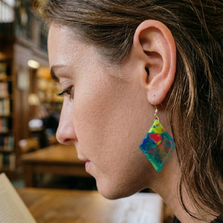 On-model style shot showing the drop length, geometric scale, and look of the upcycled green and blue diamond dangle earrings.