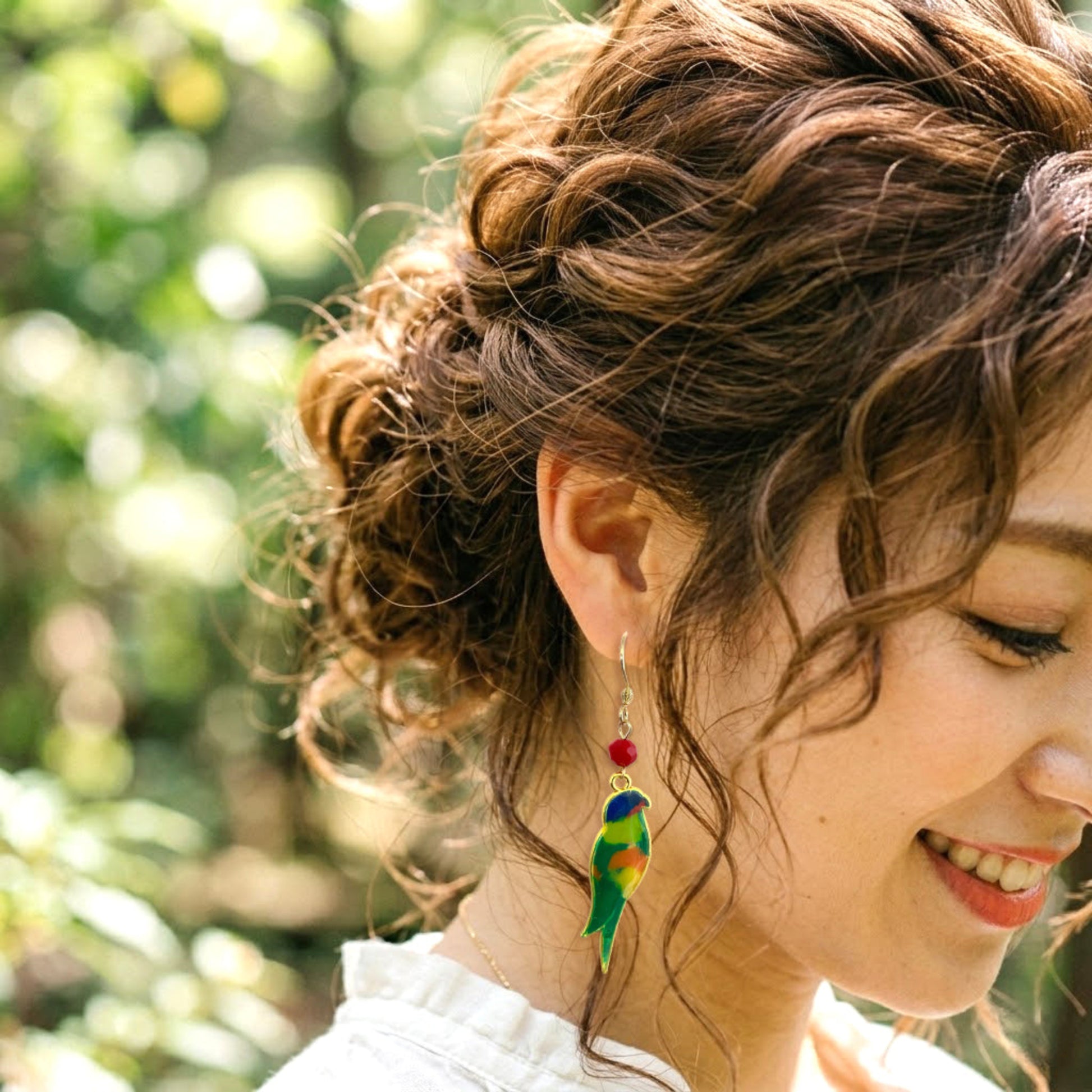 On-model style photo showcasing the fit, drop length, and scale of the colorful upcycled plastic bird silhouette earrings. Rainbow Lorikeet variant.