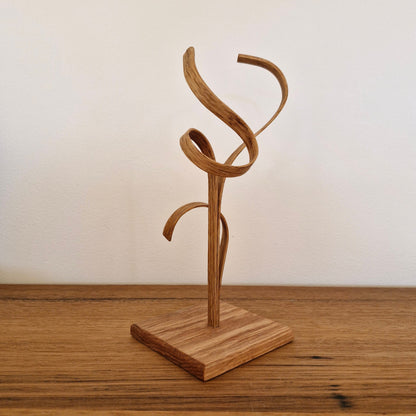 Side view of Upcycled Wood Design timber sculpture showing organic steam-bent curves and natural wood grain.